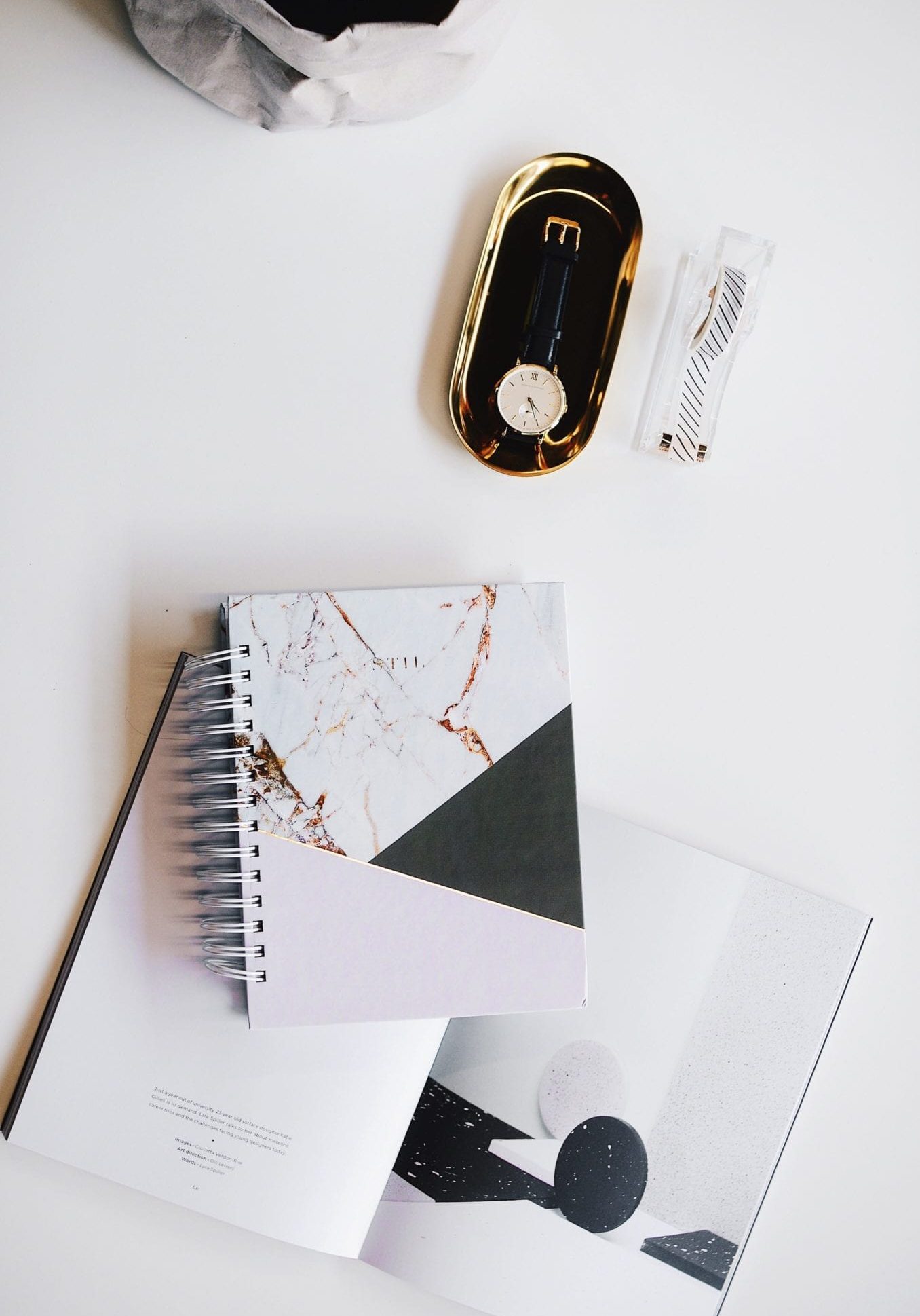 top view of a analog wrist watch with journal and magazine laying open
