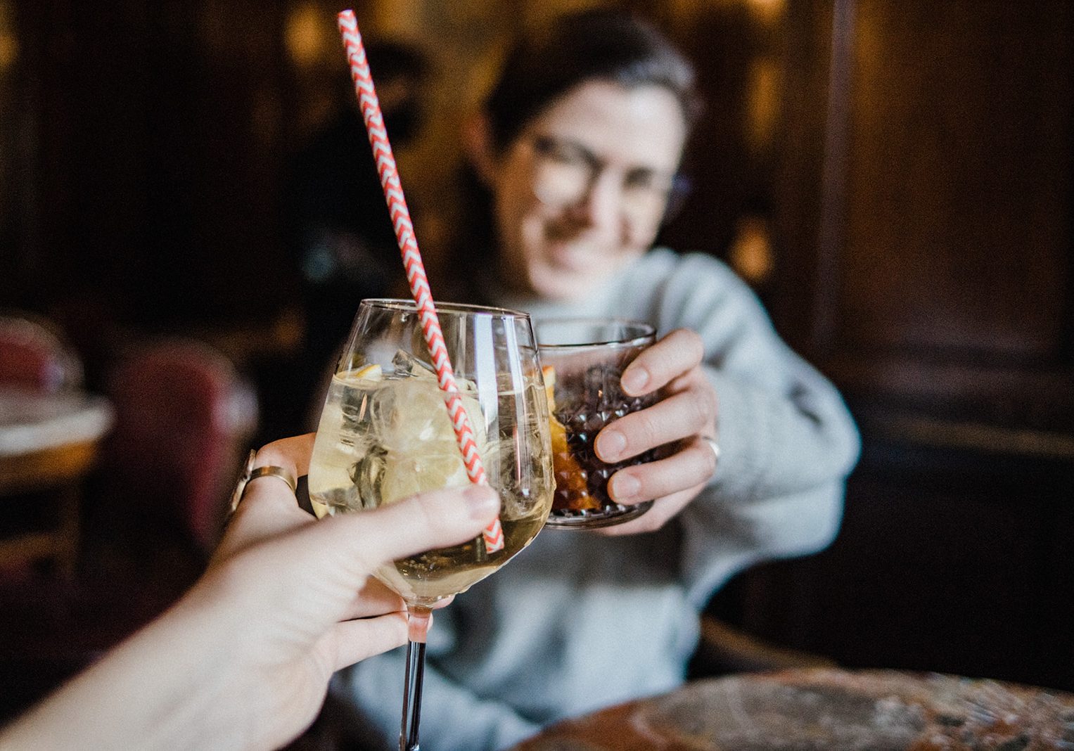 clinking glasses with a girl in background, two friends in Italy