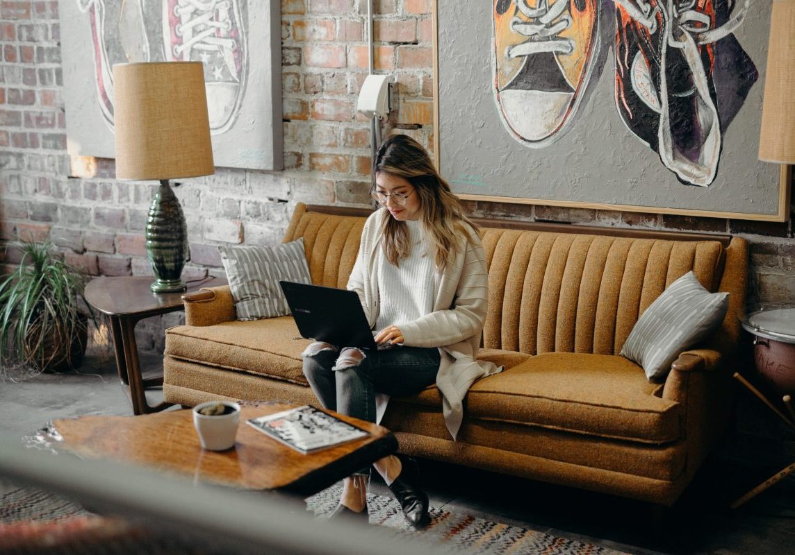 working from couch on laptop searching jobs in italy