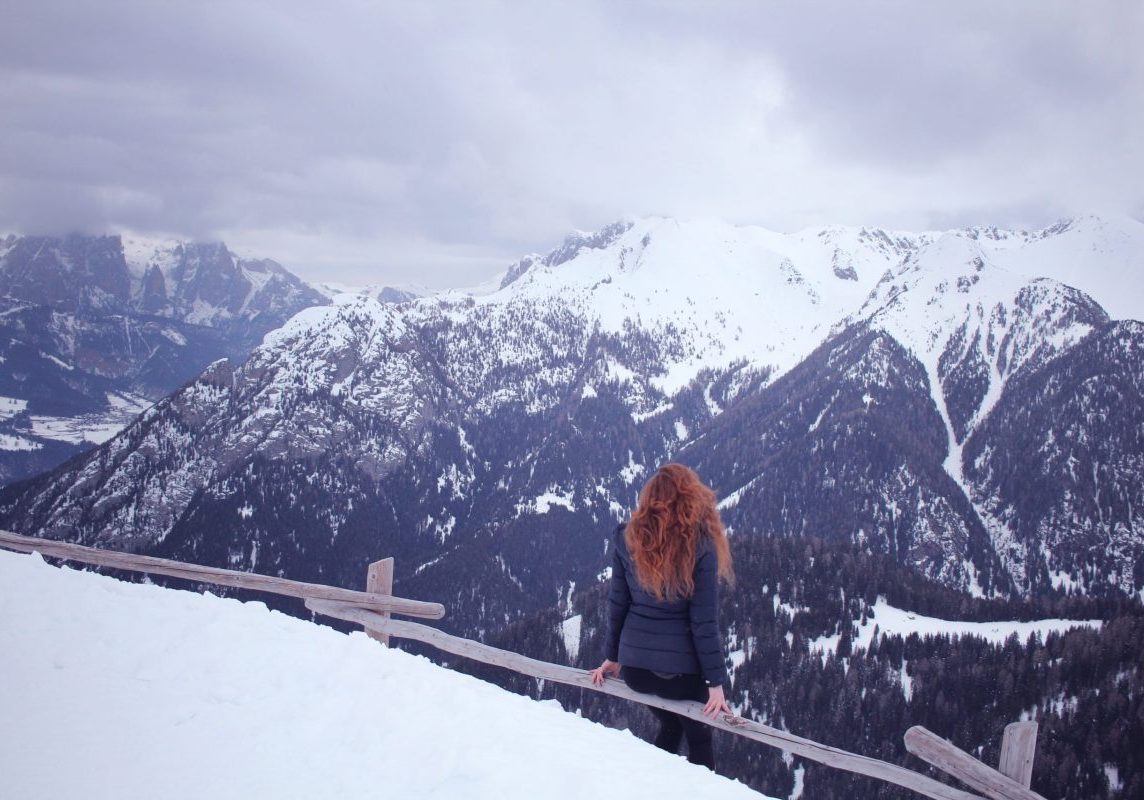 girl with read hair looking over the snowy dolomite mountains of Italy in January