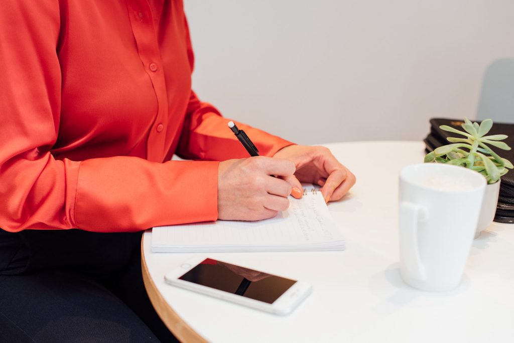 Lady sat at table with a notebook and phone planning for an event.