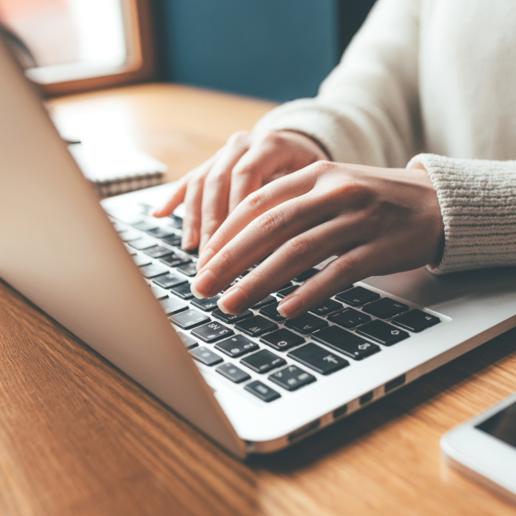 Author marketing strategist working on a laptop, creating digital marketing and branding content for authors and creatives.