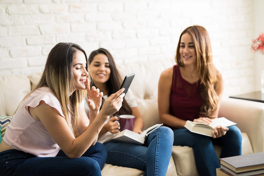Group of female friends having some fun while reading in their book club reunion